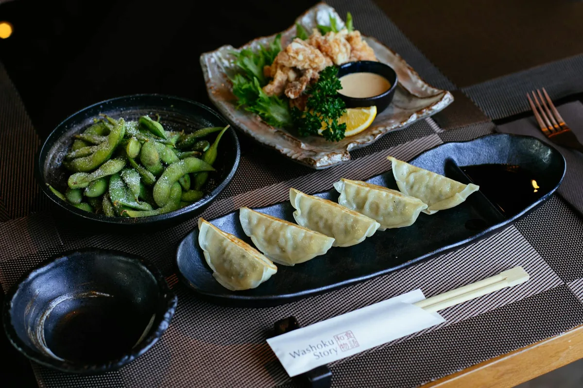 A beautifully arranged Japanese meal featuring gyoza, edamame, and karaage artfully plated.