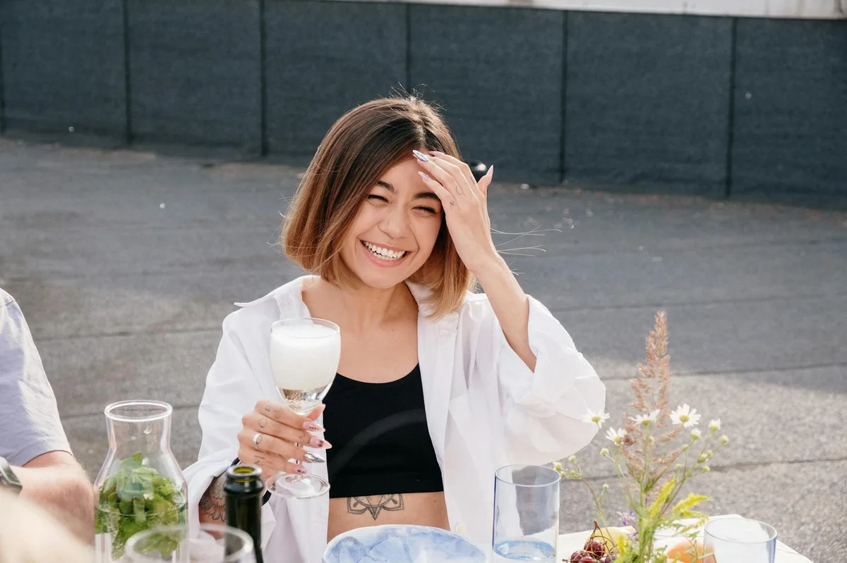 A smiling young woman enjoying a summer brunch with friends. Perfect for lifestyle and socializing themes.