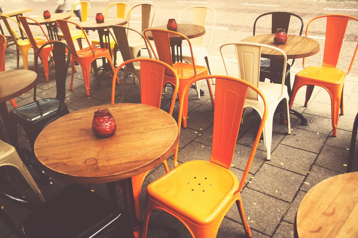 A charming outdoor cafe setting with vibrant chairs and wooden tables, perfect for a cozy day.