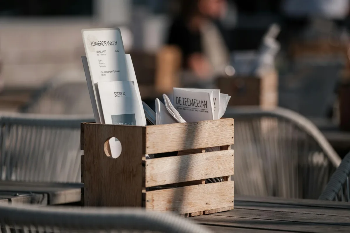 A sunlit outdoor cafe with wooden menu holder and cozy ambiance.