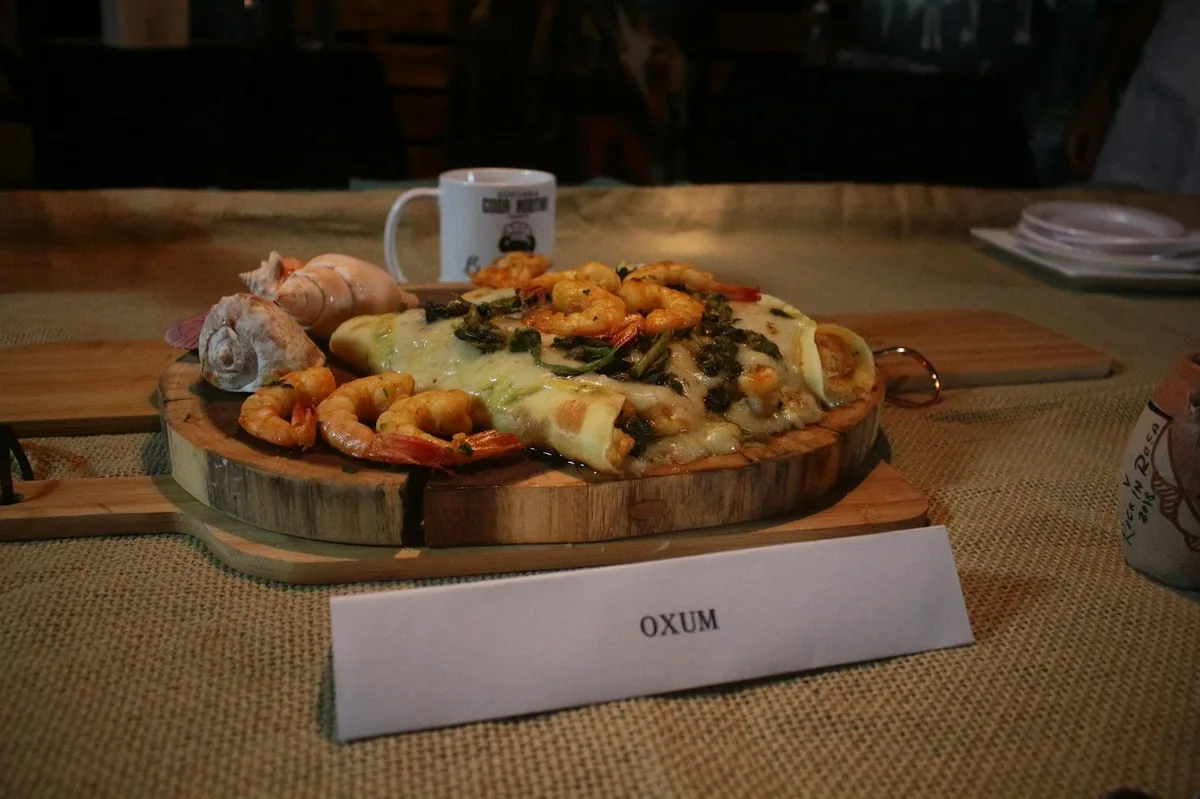 Delicious seafood pizza topped with shrimp and cheese served on a wooden board indoors.